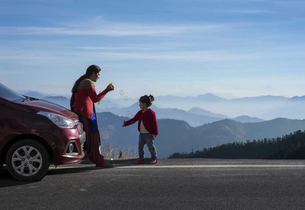 Mother and daughter enjoying the road trip and winter vacation. Car travel vacation concept photo against Himalayan mountain in the background. Travel